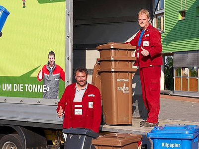 Zwei Mitarbeiter mit Abfalltonnen in Lieferwagen