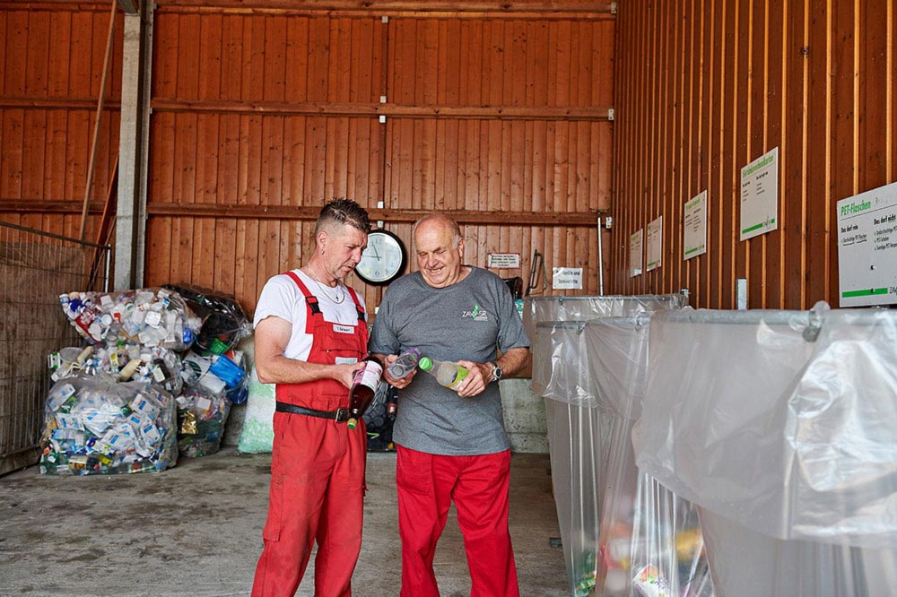 Zwei Mitarbeiter eines Wertstoffhofs beim Sortieren von Kunststoffverpackungen