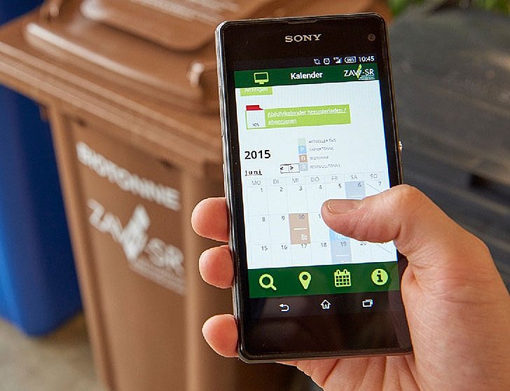 Handy mit der geöffneten ZAW-SR App und Mülltonnen im Hintergrund