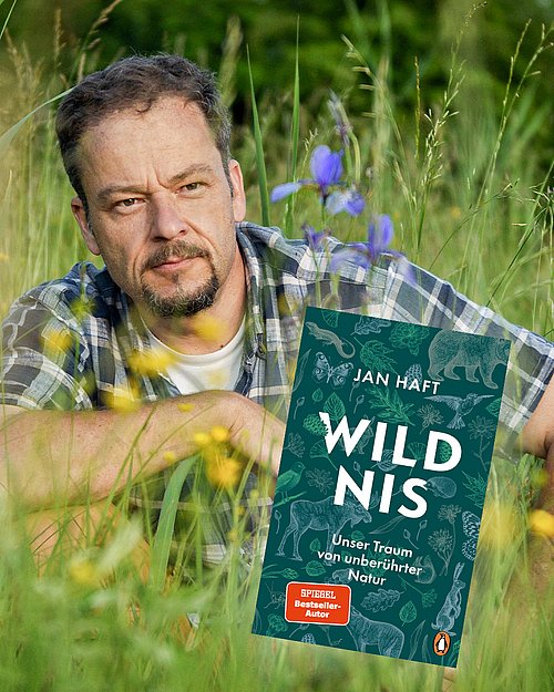 Autor Jan Haft sitzt in einer bunten Wiese - im Vordergrund sieht man sein Buch "Wildnis"