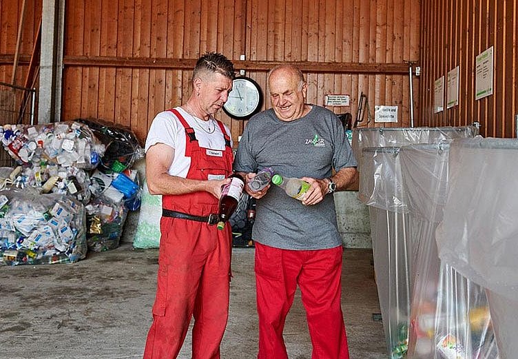 Zwei Mitarbeiter eines Wertstoffhofs beim Sortieren von Kunststoffverpackungen