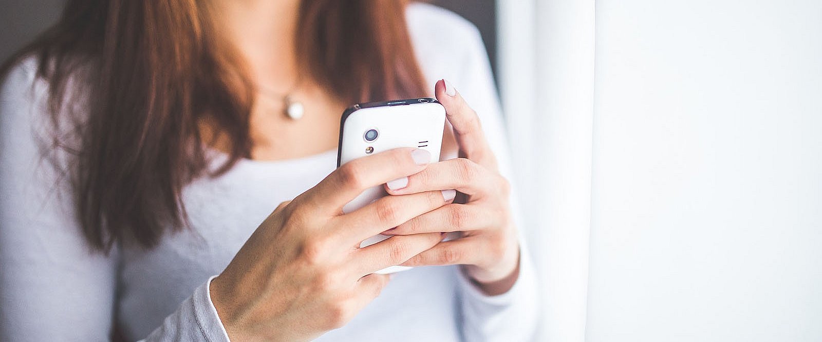 Junge Frau mit weißem Smartphone in den Händen