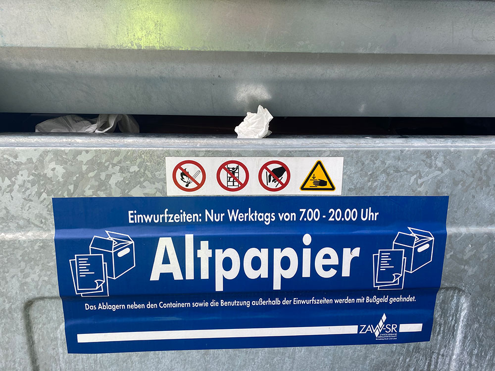 Papiertaschentuch steckt in Altpapiercontainer